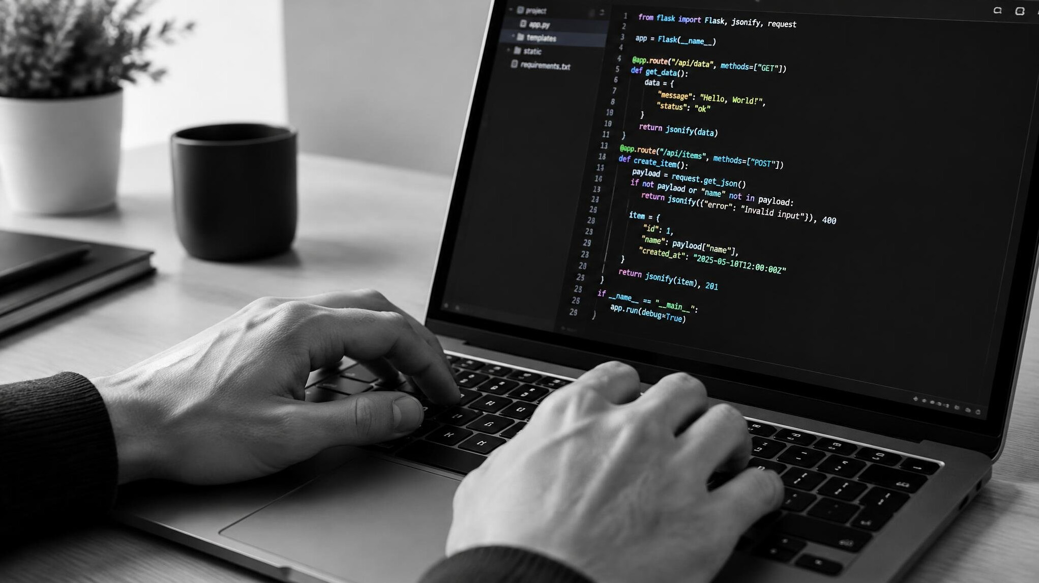Close up of hands typing on laptop keyboard with code on screen